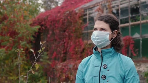 Woman in Mask Stands in Autumn Garden