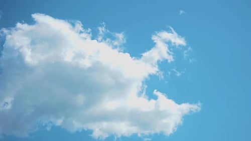 Fluffy Clouds Drifting Across Clear Blue Sky
