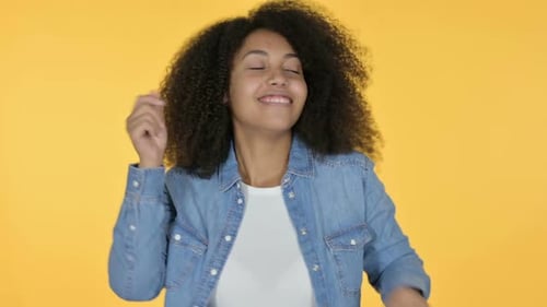 Woman Dancing with Curly Hair on Yellow Backdrop