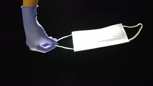 Medical Mask Held by Gloved Hand