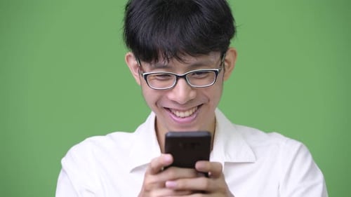 Young Man Using Smartphone in Front of Green Screen
