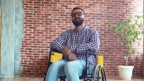 Man in Wheelchair Sits in Front of Brick Wall