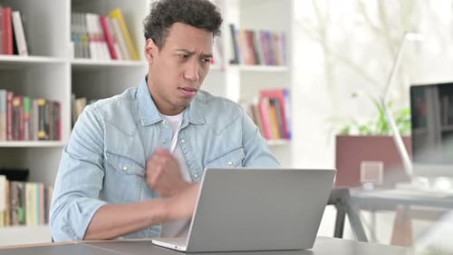 Young Adult Using Laptop Coughing at Desk