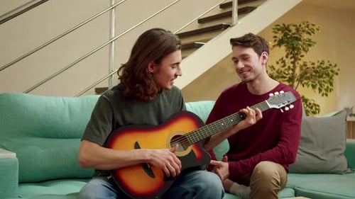 Young Men Enjoying Guitar Music on Couch