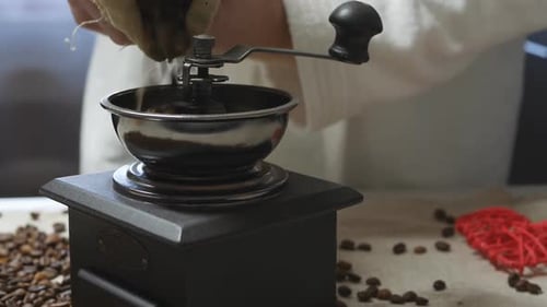 Pouring Coffee Beans into a Manual Coffee Grinder