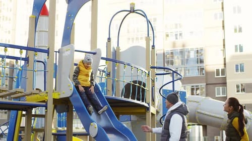 Glückliches Paar spielt mit Kind auf Urban Playground Slide