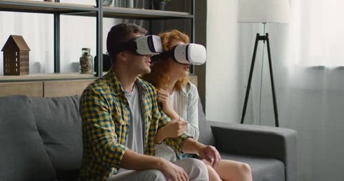 Couple Wearing VR Headsets Reacting in Living Room
