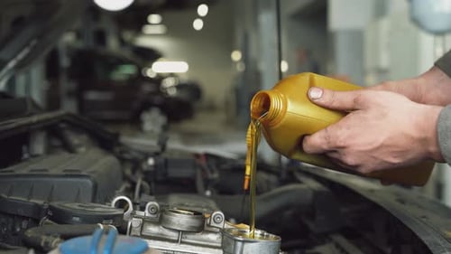Mechanic Adding New Oil to Car Engine