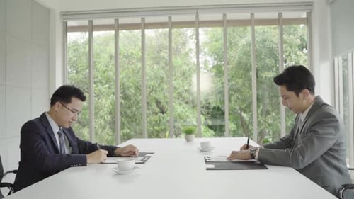Two asian confident businessman shaking hands during a meeting in the office