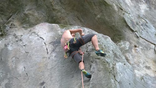 Determined Climber Clambering Up Steep Wall of Rocky Mountain