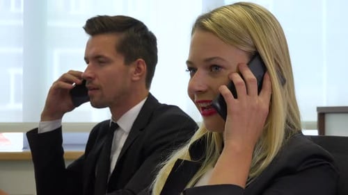 Two office workers, man and woman, talk on smartphones - closeup