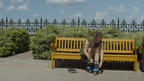 Person Putting on Rollerblades on Park Bench