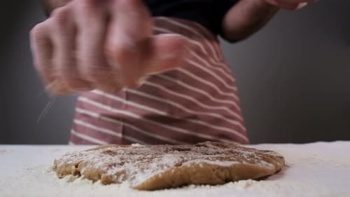 Man Sprinkles Flour on Raw Dough for Rolling Gingerbread