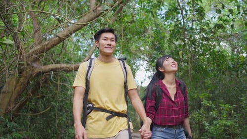 Young Asian man and woman friend traveling in the forest together, walking with happiness and fun.