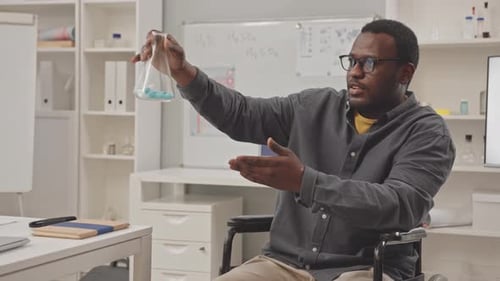 Male Teacher Lecturing with Beaker in Classroom