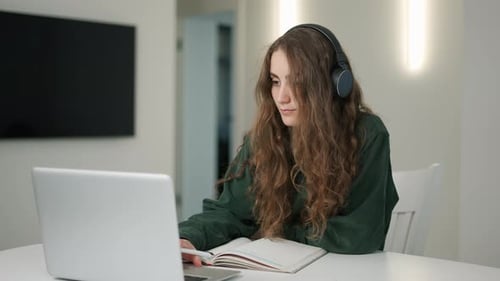 Woman with Headphones Studying at Home Using Laptop