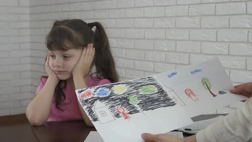 Child Presented With Drawings at Table