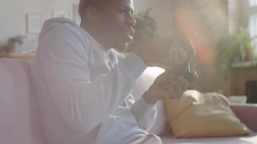 Man Plays Video Game on Couch at Home