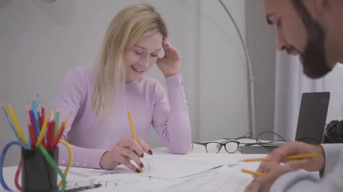 Architects Collaborating on Blueprints in the Office