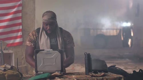 Black Military Man Using Laptop and Radio at Base