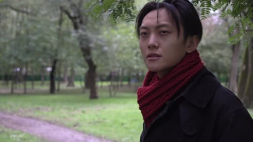 Young Asian Man Drinking Takeaway Coffee in the Park