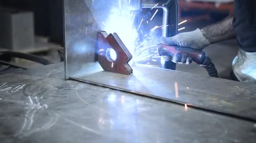 Schweißer bei der Arbeit. Arbeiter schweißt Metallteile. Schweißprozess, Funken, Flamme, Rauch.