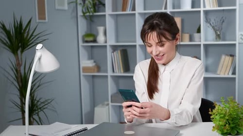 Smiling Woman Talking on Phone at Desk