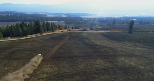 Aerial view of tractor moving on harvested field 4k