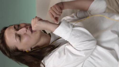 Woman Listening to Music in Bedroom with Earbuds