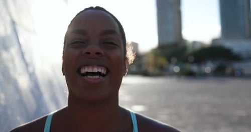 Fit african girl smiling on camera in the city after sport workout