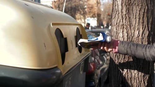 Woman Putting Carton in Recycling Bin on Street