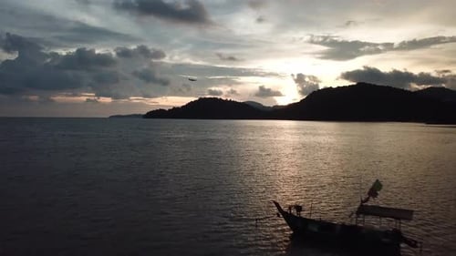 Coastal Sunset with Boat and Plane Passing