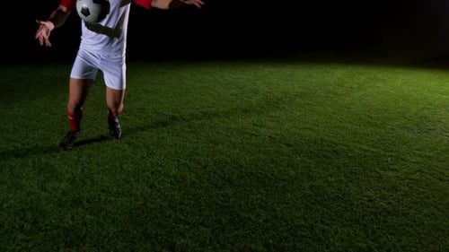 Young Adult Juggling Soccer Ball at Night