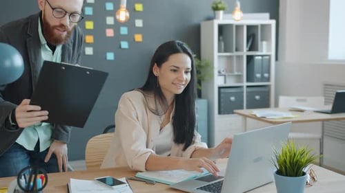 Businessman and Businesswoman Discussing Business Document in Creative Office