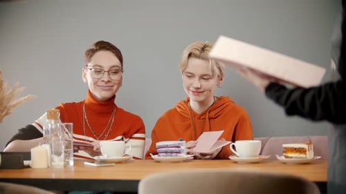 Two Friends Read Menus at Cafe Table