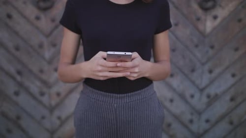An Attractive Young Lady Using a Phone in Town. Medium Shot