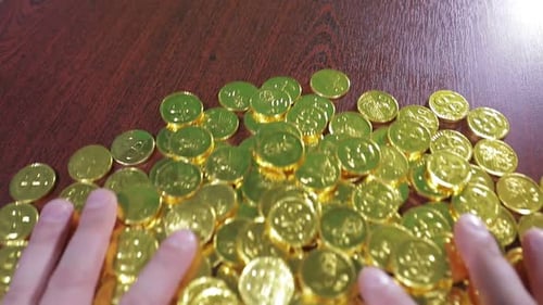 Hands Scatters Pile of Gold Coins on Table