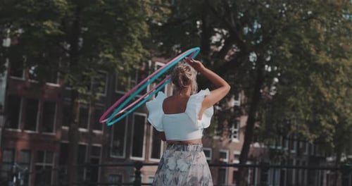 Woman spins two Hula Hoops in the street