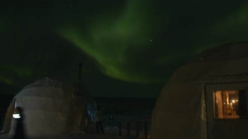 Tourists Stand Near the Igloo and Watch the Phenomenon of the Aurora Borealiss in the Night Sky