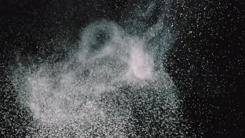 White Particles on a Black Background. Wave of Small Round Dust. Close Up. Slow Motion