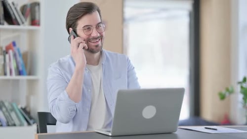 Man in Office Talking on Phone at Desk