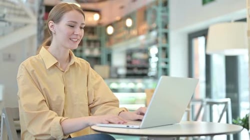 Video Chat on Laptop By Young Woman in Cafe