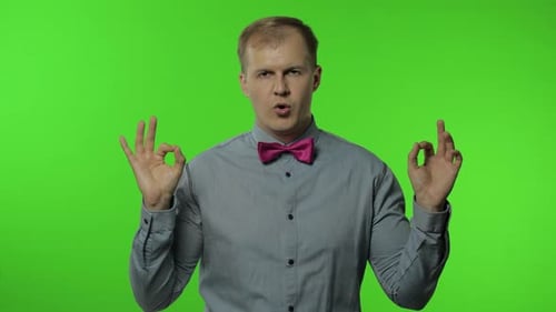 Man with Pink Bow Tie Gesturing on Green Background