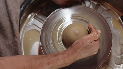 Potter donne une forme ronde à la future poterie à deux mains à l'aide du tour de potier