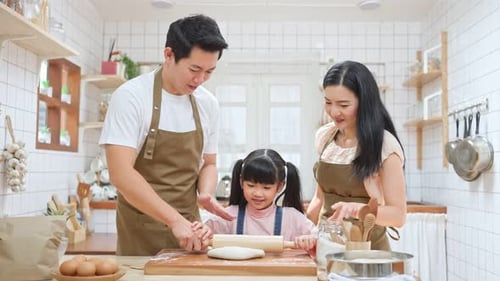 Asian happy family stay home in kitchen, parents enjoy teach little daughter baking bakery and foods