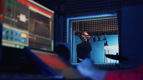 Male Rap Singer with Headphones and Sound Engineer Are Recording a New Song