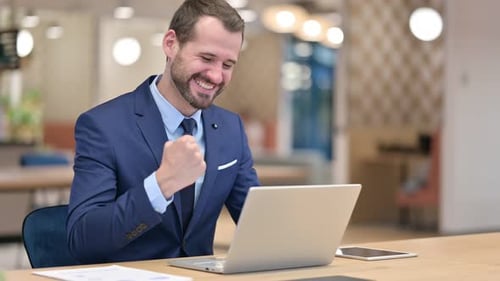 Excited Businessman Celebrating Success on Laptop in Office