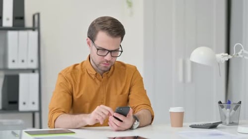 Young Man Using Smartphone in Office