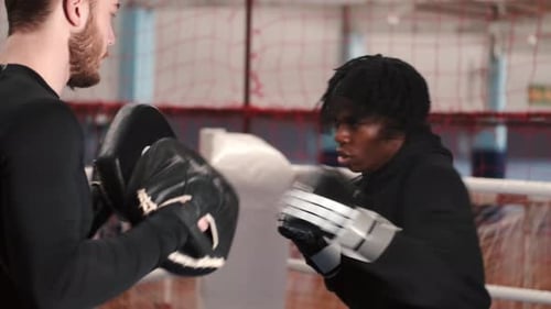 Focused Boxer Training with Coach in Boxing Ring