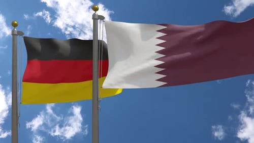 Waving Flags of Germany and Qatar Against Blue Sky